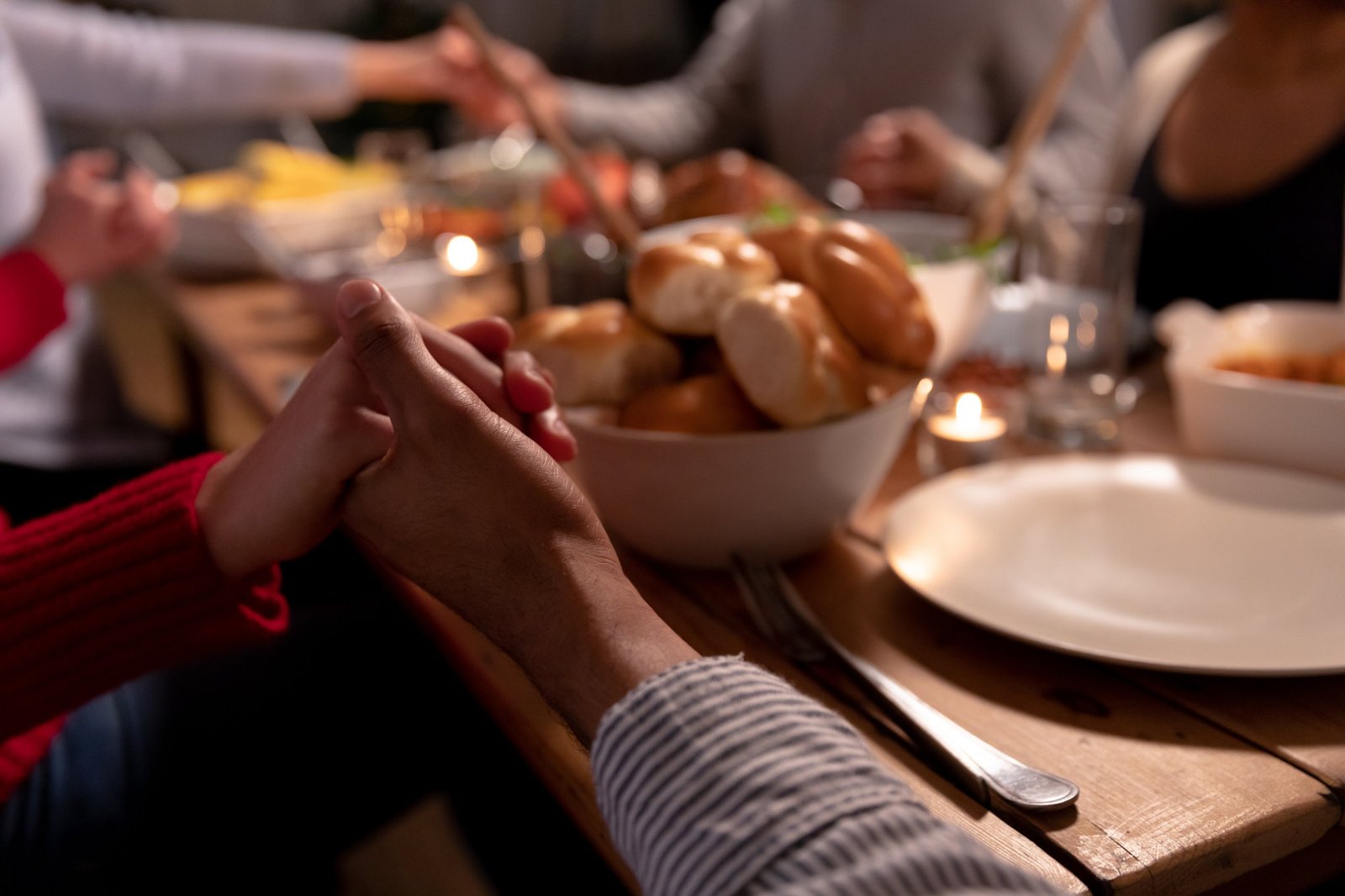 Hands joined in prayer around a Thanksgiving table